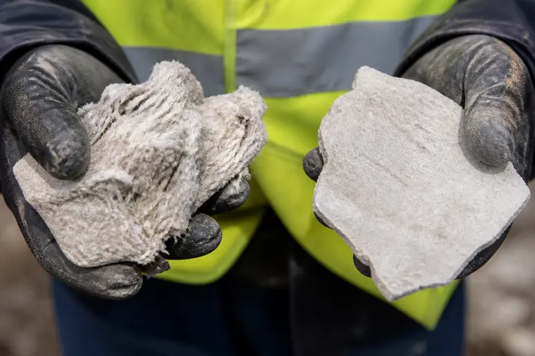 Nahaufnahme von Händen mit Handschuhen, die eine faserige Probe (links) und eine feste Platte (rechts) halten.